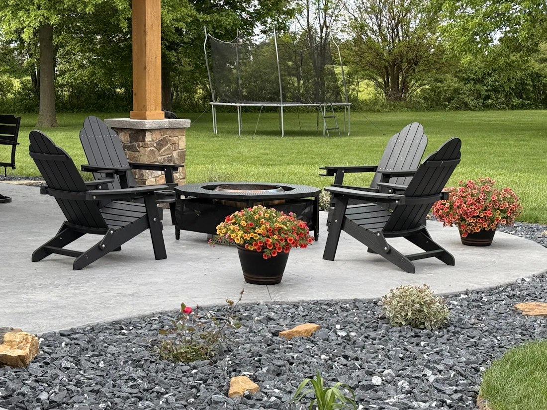 A backyard patio with chairs around a stone fire pit